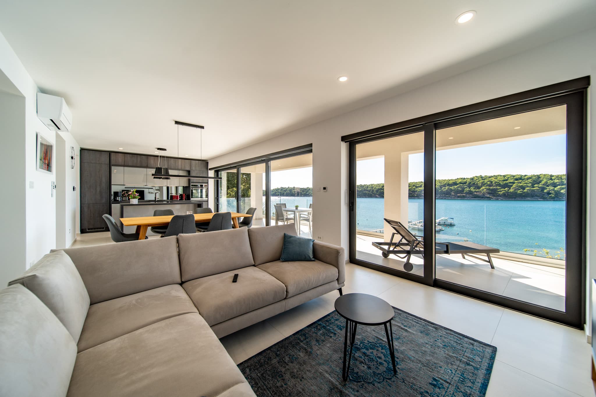 Wohnbereich von Apartment 2 mit Sofa und Blick durch die Glasfront auf das Meer